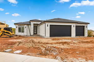 Prairie-style home with stone siding, a tile roof, stucco siding, and a garage