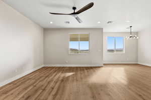 Empty room featuring light wood-type flooring, a ceiling fan, a chandelier, and recessed lighting