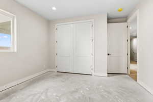 Unfurnished bedroom featuring a closet, concrete flooring, and recessed lighting
