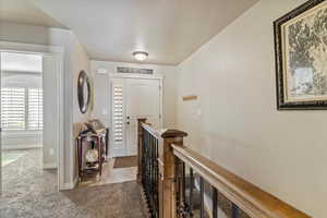 Hallway featuring light carpet, an upstairs landing, and light tile patterned floors