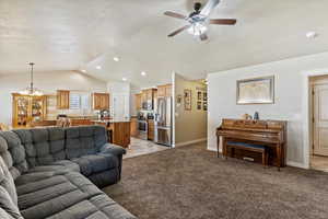 Living room with vaulted ceiling, light carpet, a ceiling fan, a chandelier, and recessed lighting
