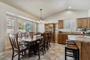Dining space featuring vaulted ceiling, a chandelier, and light tile patterned floors