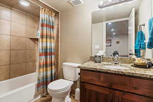 Full bath featuring shower / tub combo with curtain, vanity, light tile patterned flooring, and a textured ceiling