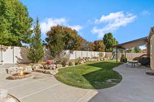 Fenced backyard featuring a patio area, a playground, and a fire pit