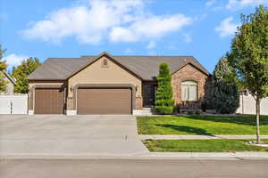 View of front of home with an attached garage, driveway, roof with shingles, brick siding, and stucco siding
