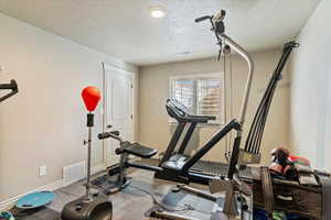 Workout room featuring a textured ceiling and baseboards
