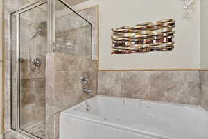 Full bath featuring a jetted tub and a shower stall