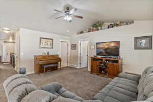 Living area featuring vaulted ceiling, light colored carpet, and a ceiling fan