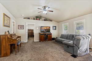 Carpeted living room with lofted ceiling and ceiling fan