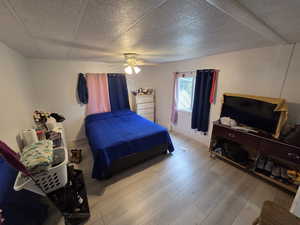 Bedroom with wood finished floors, a ceiling fan, and a textured ceiling