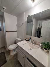 Full bathroom featuring vanity, a textured ceiling, a shower with shower curtain, and dark tile patterned flooring