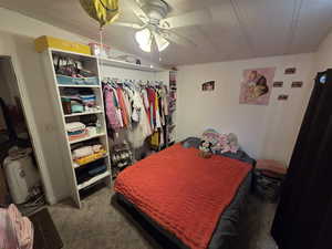 Added bedroom with dark colored carpet, a ceiling fan, and a closet