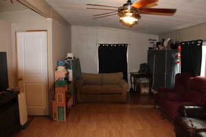 Living room with lofted ceiling, light wood finished floors, and a ceiling fan