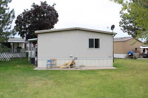 Rear view of house with a patio, a lawn, and flat storage area.