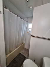 Full bathroom with a textured ceiling, shower / tub combo with curtain, and tile patterned flooring