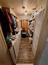 Laundry room with dark wood-type flooring, a heating unit, a textured ceiling, and washing machine and dryer