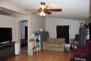 Living room with light wood-style floors, and a ceiling fan included added room.
