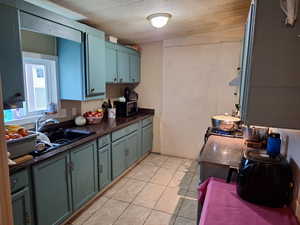 Kitchen with new ceramic tile patterned floors, blue cabinetry, and vaulted ceiling