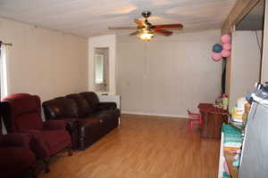 Living room area featuring wood finished floors and a ceiling fan