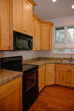 Kitchen with black appliances, tile counters, light wood finished floors, light brown cabinetry, and recessed lighting