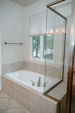 Full bathroom featuring a bath, a shower stall, and tile patterned flooring