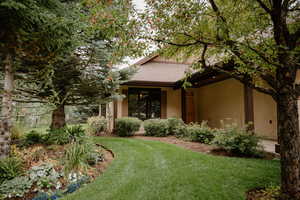 View of front facade with a front yard, stucco siding, and roof with shingles