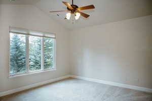 Carpeted empty room with vaulted ceiling and ceiling fan