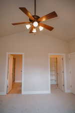 Unfurnished bedroom featuring vaulted ceiling, a spacious closet, light carpet, and a ceiling fan