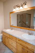 Full bathroom with double vanity, a shower stall, and light tile patterned floors