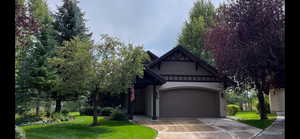 View of front of home with a front lawn, an attached garage, driveway, and stucco siding