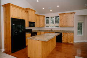 Kitchen with light brown cabinets, black appliances, dark wood-style floors, recessed lighting, and lofted ceiling
