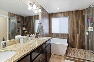 Full bath featuring double vanity, a walk in shower, a freestanding bath, light tile patterned floors, and recessed lighting