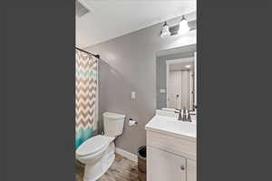 Full bath featuring vanity, curtained shower, and light wood finished floors
