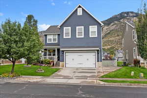 Traditional home featuring stucco siding, concrete driveway, a garage, a porch, and a mountain view