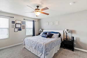 Carpeted bedroom featuring baseboards and ceiling fan