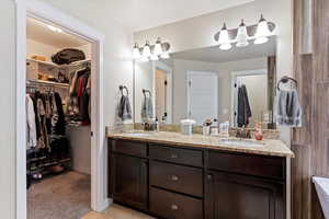 Bathroom with double vanity, a walk in closet, and light tile patterned floors