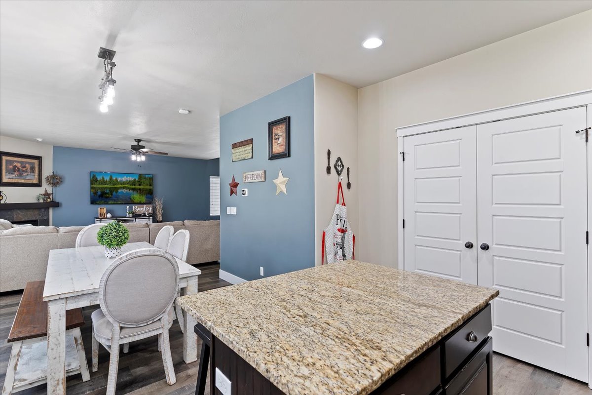 Kitchen with dark wood-style flooring, hanging light fixtures, a center island, open floor plan, and dark brown cabinets