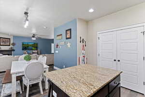 Kitchen with dark wood-style flooring, hanging light fixtures, a center island, open floor plan, and dark brown cabinets