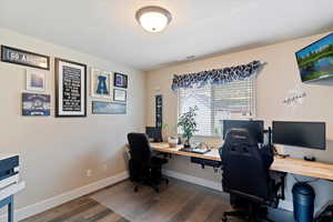 Office area featuring dark wood-style flooring and baseboards
