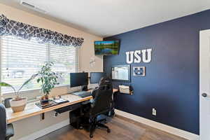 Office space featuring dark wood-style flooring and baseboards