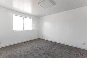 Primary bedroom with dark colored carpet and baseboards