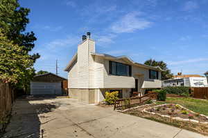 Bi-level home with an outbuilding, a chimney, and a detached garage