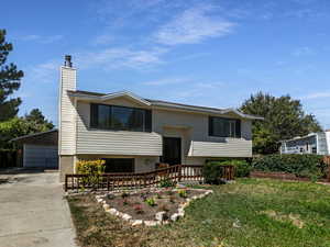Split foyer home with brick siding, a chimney, and a garage