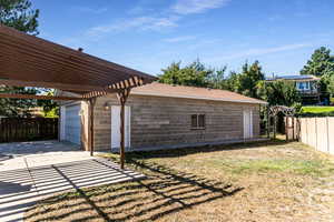 View of yard featuring a garage and a pergola