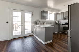 Kitchen featuring gray cabinetry, stainless steel appliances, french doors, and dark wood-type flooring