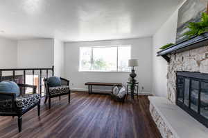Living room featuring dark wood-style floors, a fireplace, and a textured ceiling