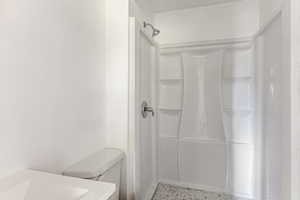 Full bath with dark speckled floor and a stall shower