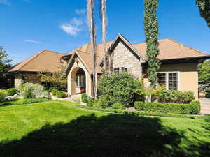 View of front of property featuring a front yard, stone siding, and stucco siding