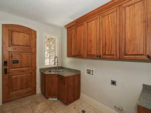 Washroom with hookup for a washing machine, cabinet space, stone tile flooring, electric dryer hookup, and gas dryer hookup
