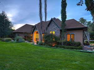 View of front of property featuring a front yard, stone siding, and stucco siding